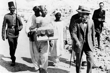 Говард Картер выходит из гробницы в сопровождении работников со статуей Тутанхамона.